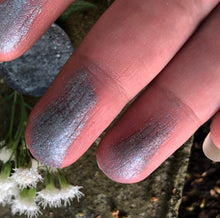 Load image into Gallery viewer, swatches of gun metal grey eyeshadow on fingertips in front of a baby&#39;s breath flower 
