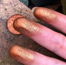 Load image into Gallery viewer, finger swatch of copper eyeshadow in front of some rocks

